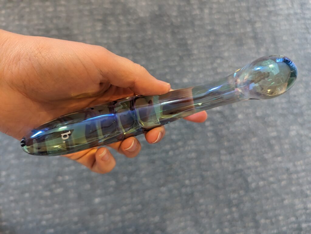 The Kalii held in the palm, the small biird b. logo visible on the rainbow glass shaft.