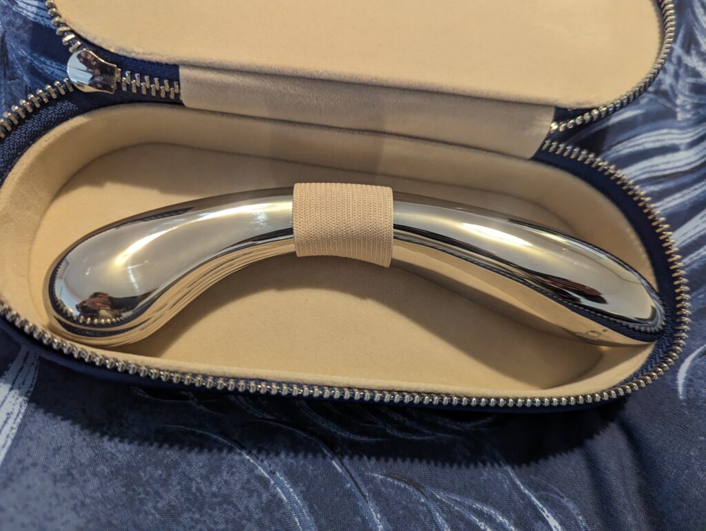 A pair of hands cradling the Kalii over patterned bed linen.